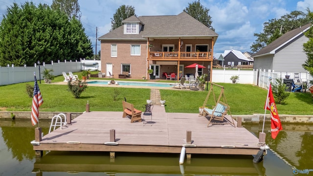 view of dock with a yard and a pool side deck with water view