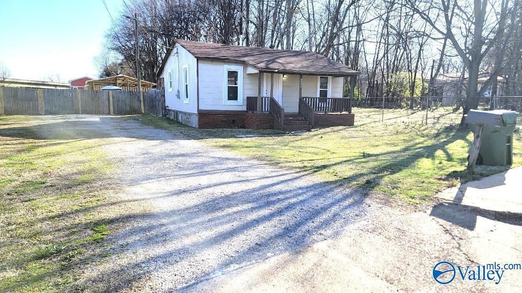 view of front of property featuring a front lawn, fence, gravel driveway, a shingled roof, and crawl space