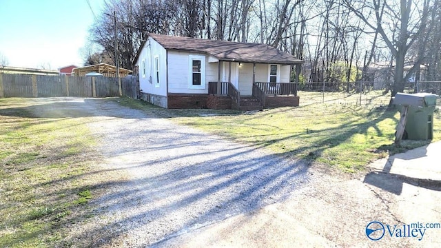 view of front of property featuring a front lawn, fence, gravel driveway, a shingled roof, and crawl space