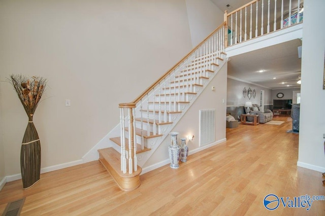 stairs featuring baseboards, visible vents, wood finished floors, and ornamental molding