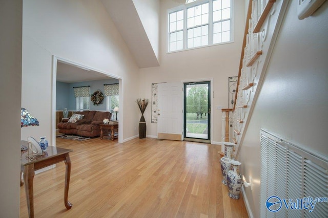 foyer with stairs, plenty of natural light, a high ceiling, and wood finished floors