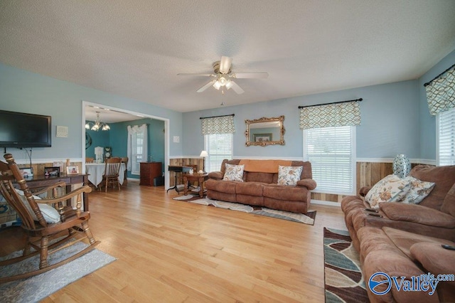 living area with a wainscoted wall, a textured ceiling, and wood finished floors