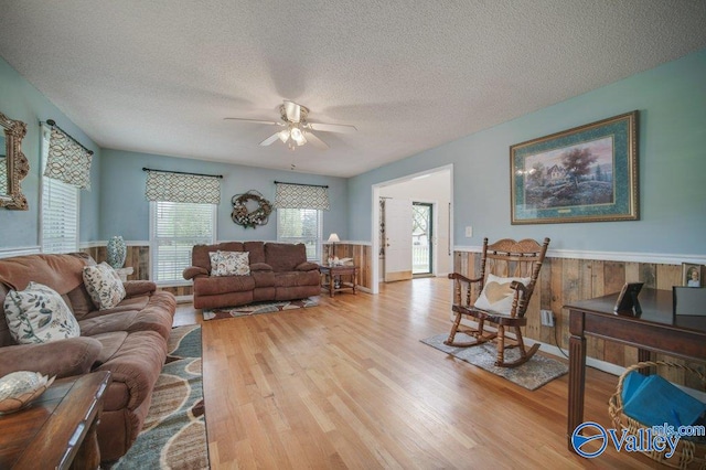 living area featuring a wainscoted wall, a textured ceiling, and wood finished floors