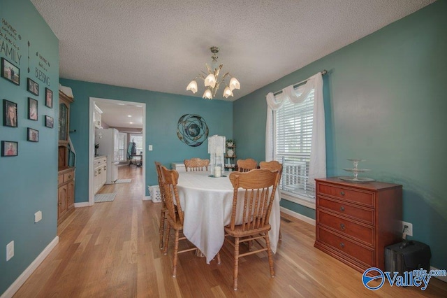 dining room featuring an inviting chandelier, a textured ceiling, baseboards, and light wood-style floors