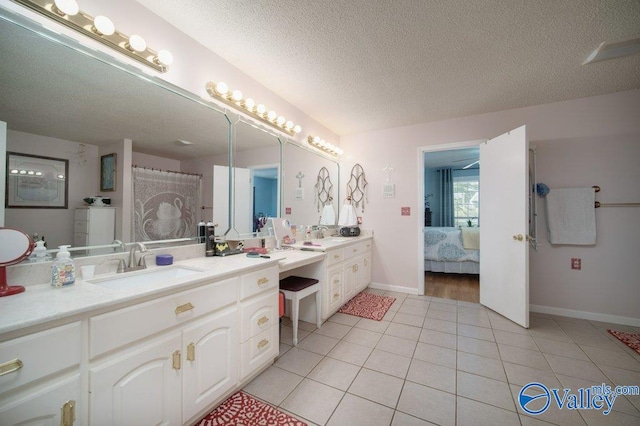 full bath with a textured ceiling, connected bathroom, vanity, baseboards, and tile patterned floors