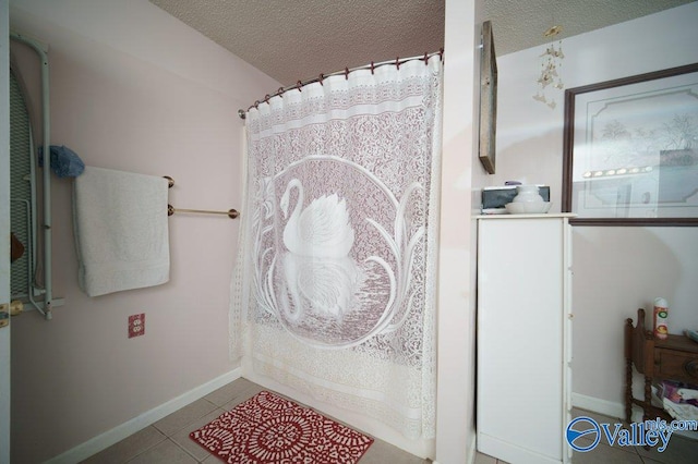 bathroom featuring tile patterned flooring, baseboards, a textured ceiling, and a shower with curtain