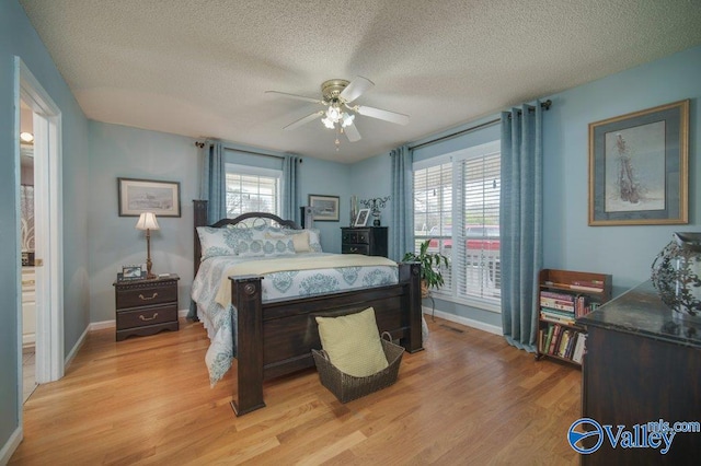 bedroom featuring visible vents, baseboards, a ceiling fan, a textured ceiling, and light wood-type flooring