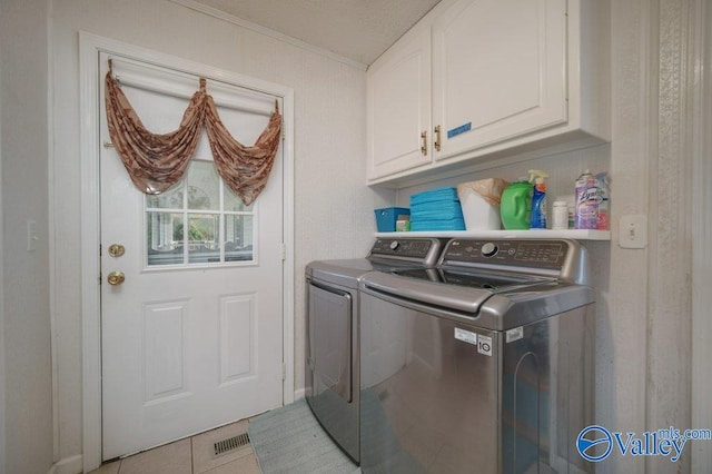 clothes washing area featuring cabinet space, visible vents, washing machine and clothes dryer, and light tile patterned flooring