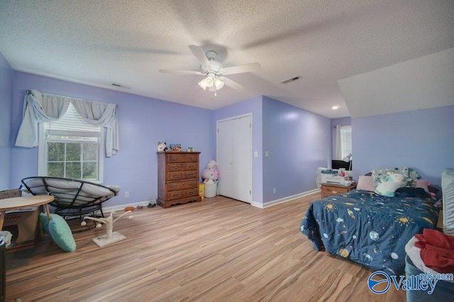 bedroom with visible vents, baseboards, a textured ceiling, and light wood finished floors