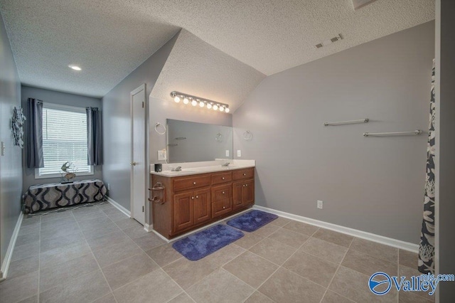 bathroom with double vanity, baseboards, visible vents, vaulted ceiling, and a sink