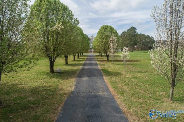 surrounding community with aphalt driveway and a lawn