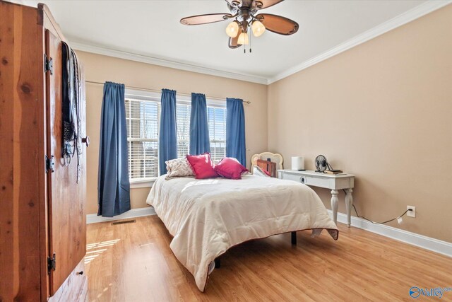 bedroom featuring light wood-style floors, visible vents, crown molding, and baseboards