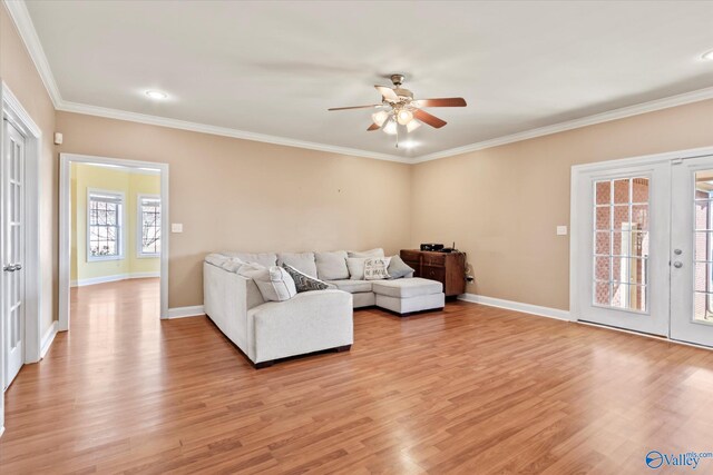 living area featuring baseboards, french doors, light wood-type flooring, and crown molding