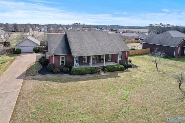 view of front of house featuring a porch, brick siding, an outdoor structure, fence, and a front yard