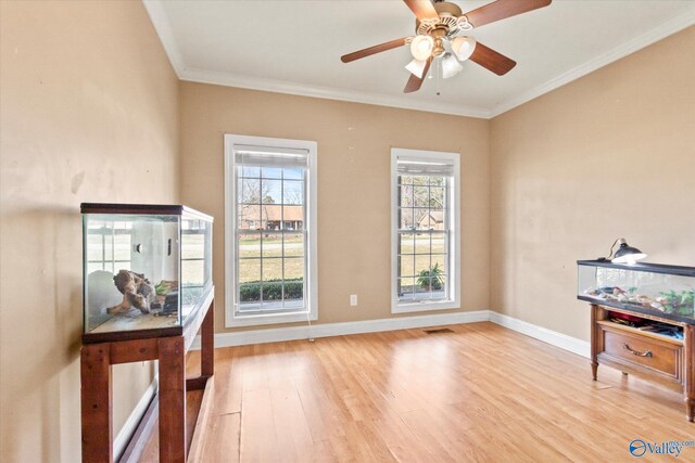 interior space featuring light wood-style floors, a ceiling fan, baseboards, and crown molding