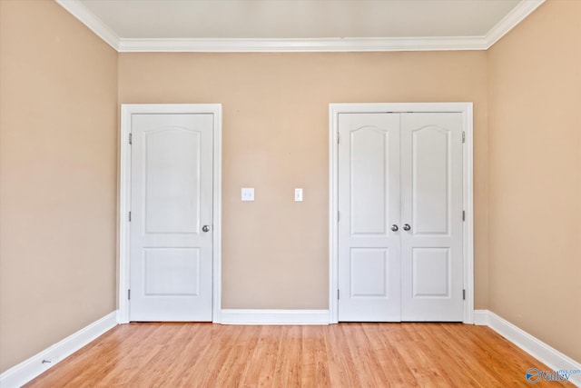 unfurnished bedroom featuring crown molding, light wood-style floors, a closet, and baseboards