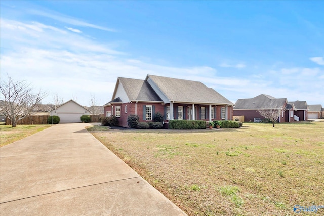 view of front facade with a garage, an outbuilding, fence, a front yard, and brick siding
