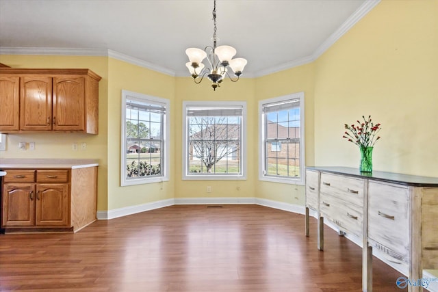 unfurnished dining area featuring ornamental molding, dark wood finished floors, baseboards, and an inviting chandelier