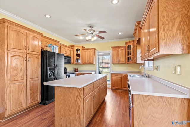 kitchen with a sink, black appliances, wood finished floors, and a kitchen island