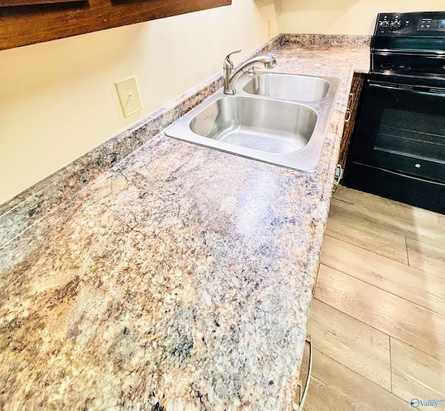 kitchen featuring black electric range, light countertops, a sink, and wood finished floors