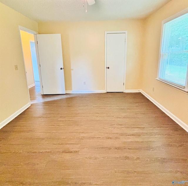 empty room with a ceiling fan, wood finished floors, and baseboards