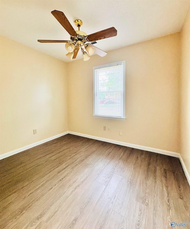 unfurnished room with a ceiling fan, wood finished floors, and baseboards