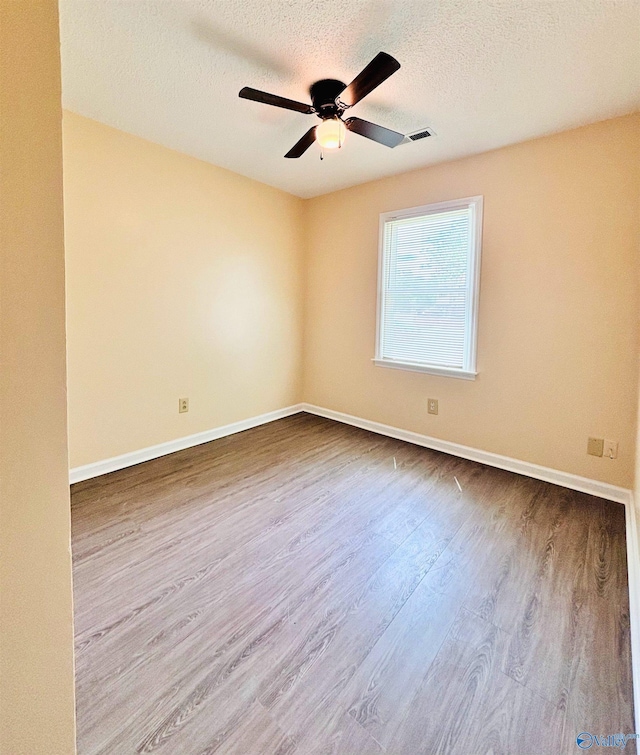 empty room featuring ceiling fan, a textured ceiling, baseboards, and dark wood-style floors
