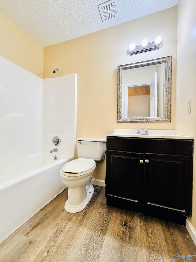 bathroom featuring a textured ceiling, toilet, visible vents, vanity, and wood finished floors