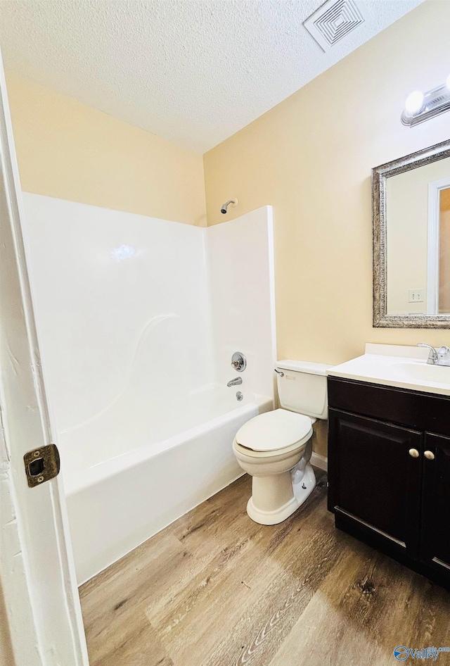 bathroom featuring toilet, wood finished floors, washtub / shower combination, visible vents, and vanity