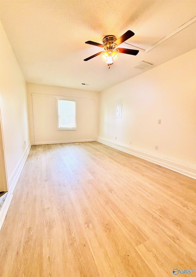 spare room with a ceiling fan, baseboards, light wood-style flooring, and a textured ceiling