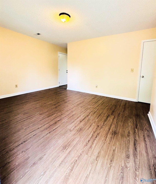 spare room featuring baseboards, a textured ceiling, and wood finished floors