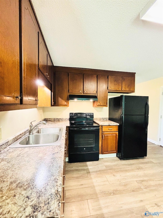 kitchen featuring black appliances, light countertops, light wood-style flooring, and a sink