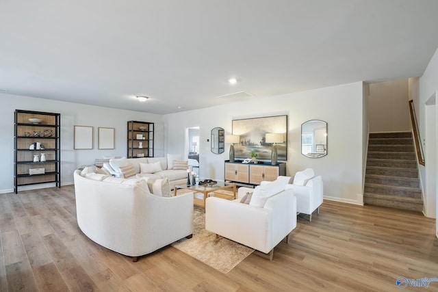 living area featuring stairway, baseboards, and light wood-style flooring