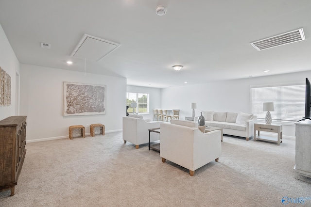 living room with attic access, baseboards, visible vents, and light colored carpet
