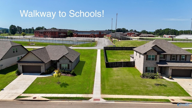 view of front of home with a residential view, a front lawn, concrete driveway, and fence