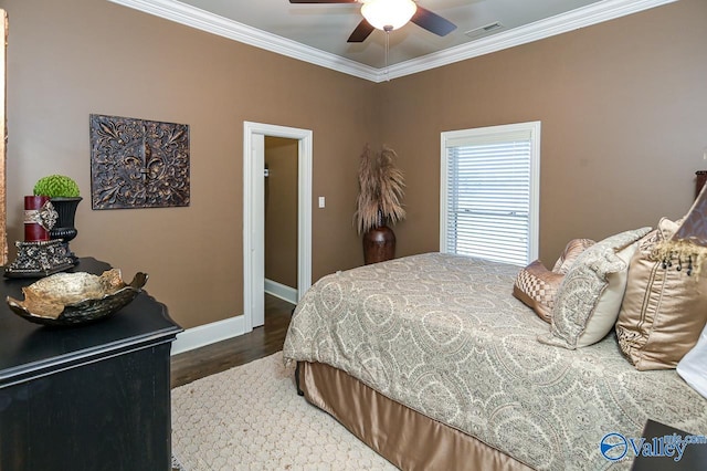 bedroom with crown molding, wood finished floors, baseboards, visible vents, and ceiling fan