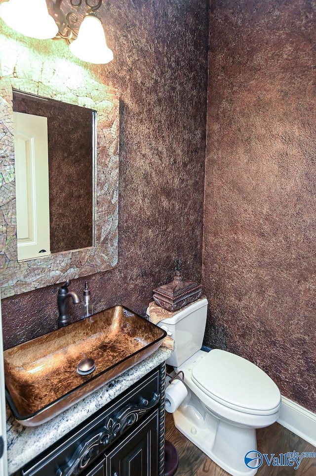 bathroom featuring toilet, vanity, and baseboards
