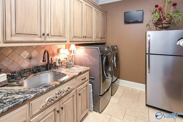 laundry room featuring stone tile floors, a sink, washing machine and clothes dryer, baseboards, and cabinet space