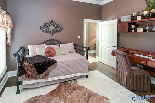 bedroom featuring ornamental molding, baseboards, and wood finished floors