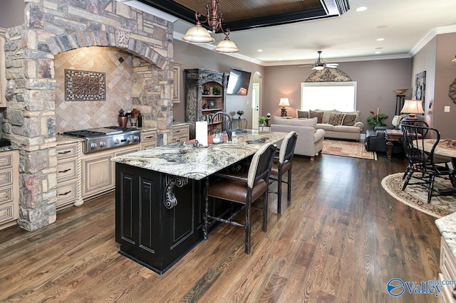kitchen featuring stainless steel gas cooktop, cream cabinetry, ceiling fan, ornamental molding, and dark wood-style flooring