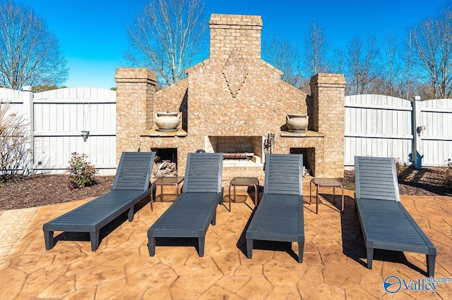 view of patio / terrace with an outdoor brick fireplace and fence