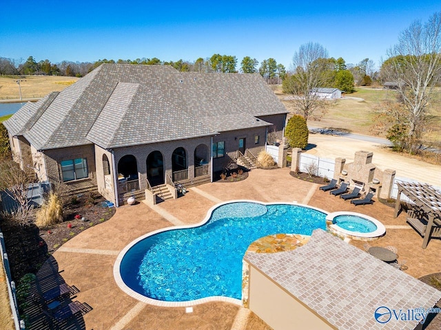 view of pool with fence, a pool with connected hot tub, and a patio area