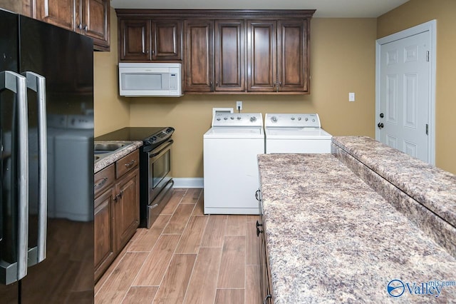 clothes washing area with baseboards, wood tiled floor, independent washer and dryer, and laundry area