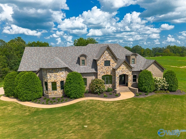 french country style house with a front lawn and stone siding
