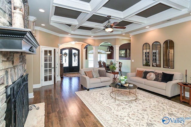 living area featuring coffered ceiling, decorative columns, dark wood-style flooring, a ceiling fan, and a fireplace