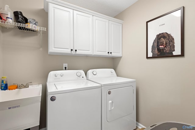 clothes washing area with a sink, cabinet space, and washing machine and dryer