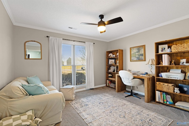 carpeted home office with visible vents, a ceiling fan, crown molding, and baseboards