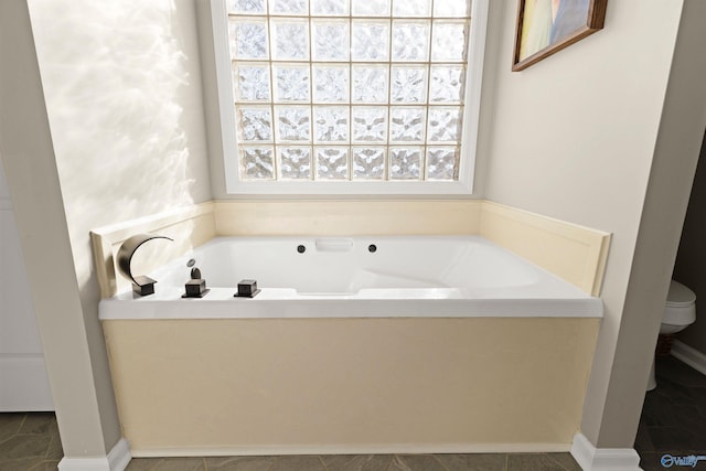 bathroom featuring a garden tub, toilet, and tile patterned floors