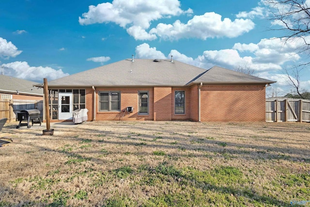 rear view of house featuring brick siding, a patio area, a yard, and a fenced backyard