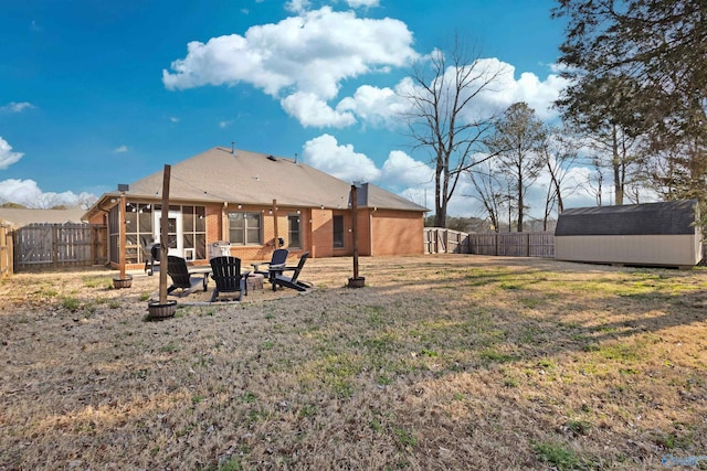 rear view of property featuring a storage shed, a fire pit, brick siding, and a fenced backyard